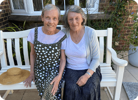 Summerlands | an image showing a resident and a family member sat outside in the summer sun. Emphasising that our home is covid free